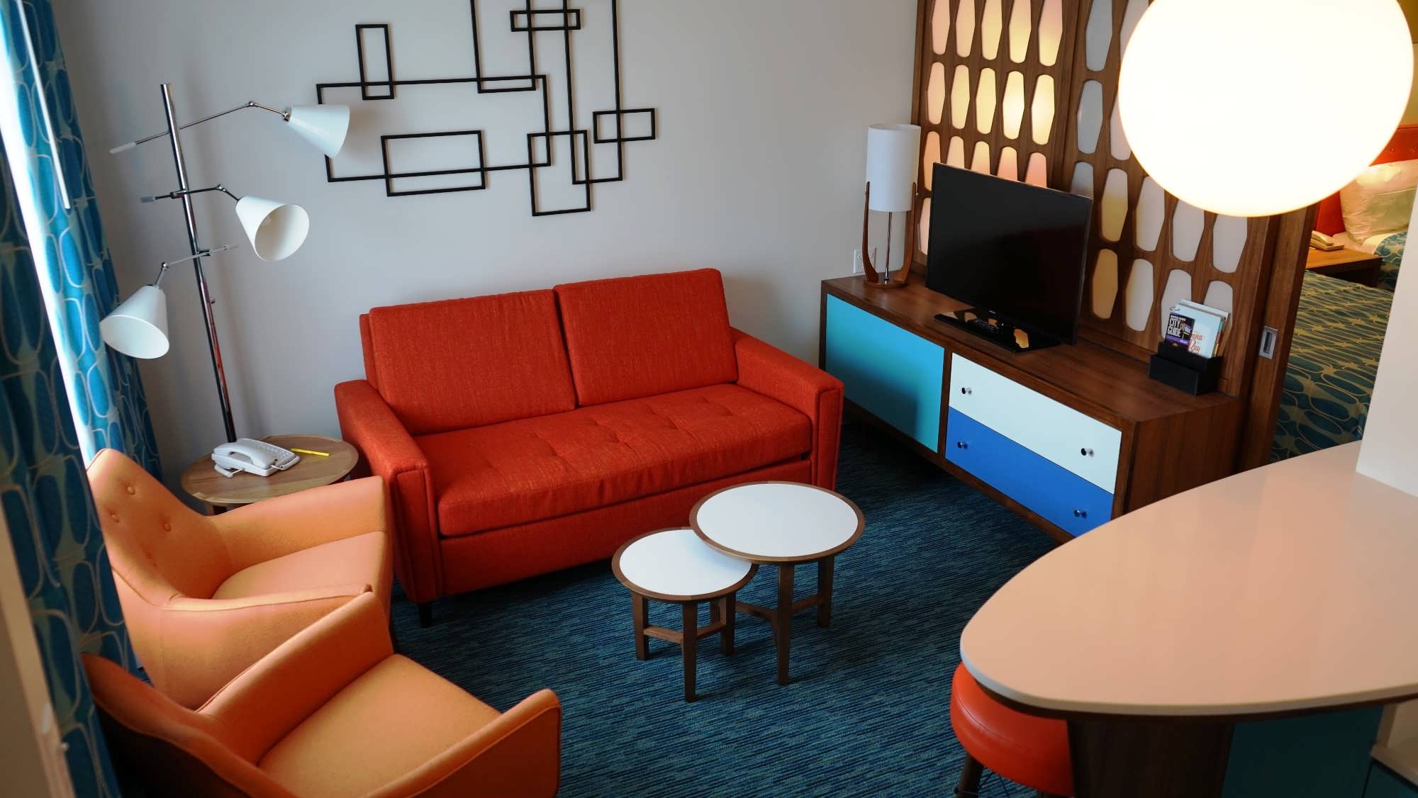 1950's style furniture with a modern flatscreen tv in the living space of a family suite at Cabana Bay