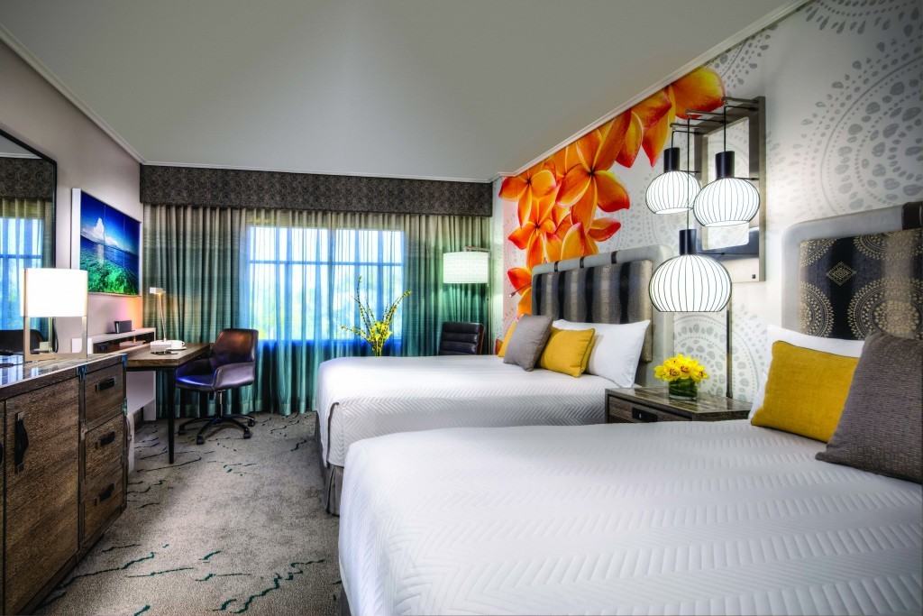 A double queen room at Royal Pacific Resort with an accent wall of orchids and tropical patterns