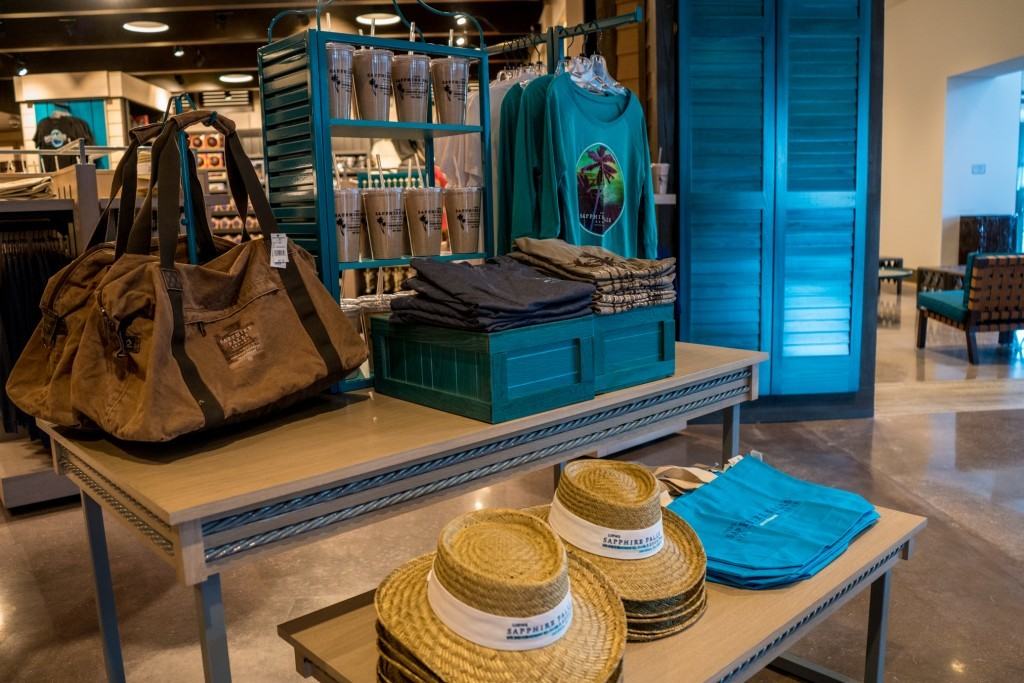 A shop display of hats, shirts, bags, and mugs from Sapphire Falls Resort