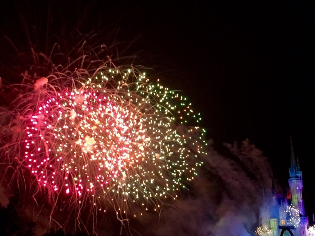 Red and gold fireworks exploding overhead to the left of Cinderall'as castle.