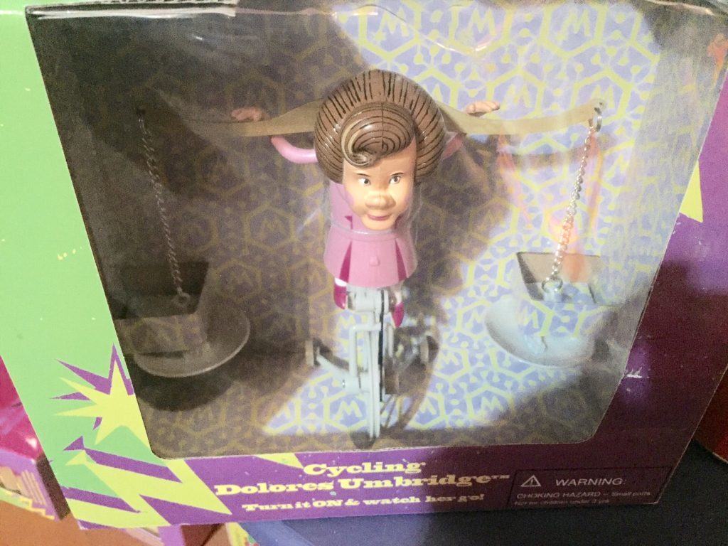 Dolores Umbridge small plastic toy riding a unicycle carrying buckets.