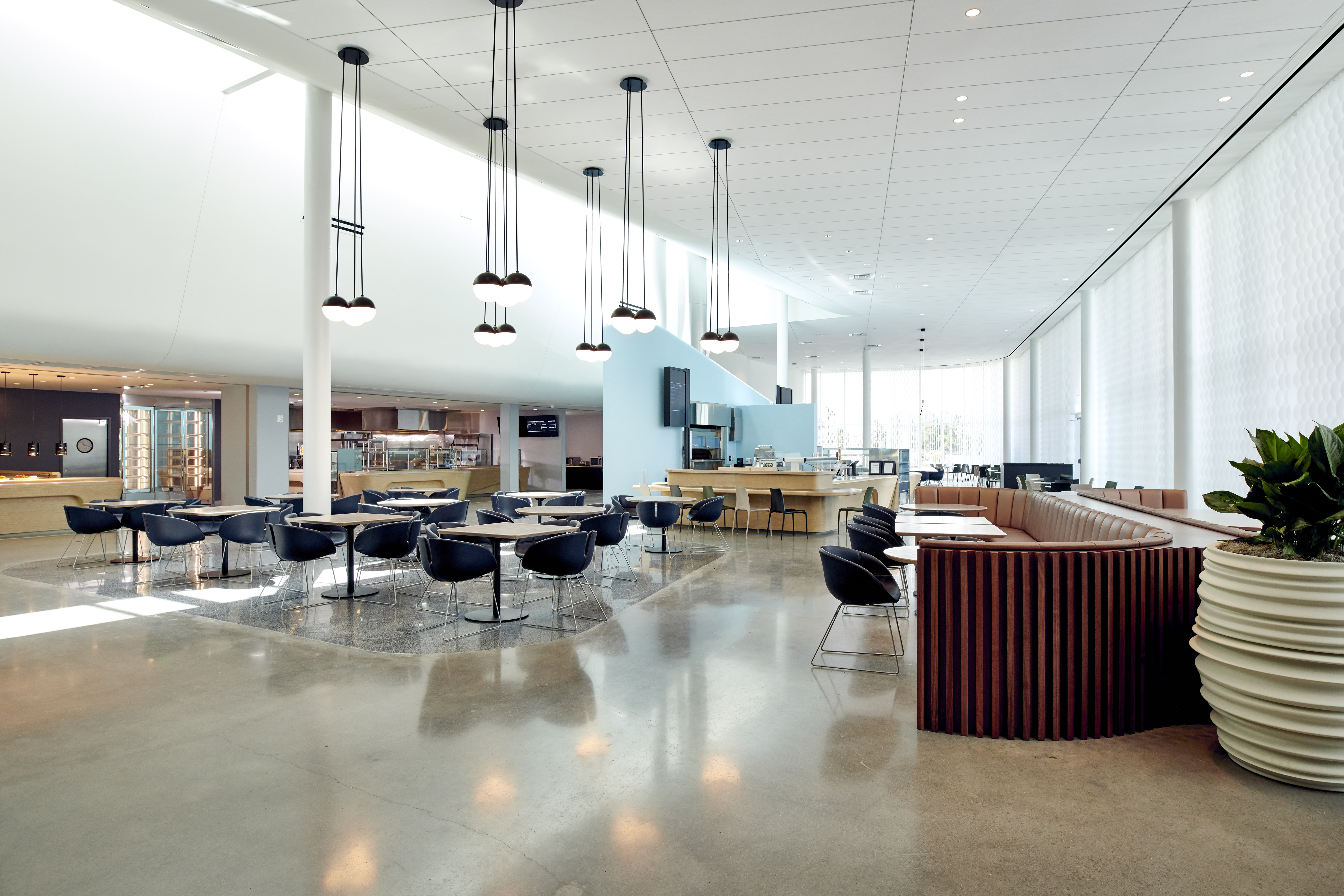 Seating at Urban Pantry in Aventura Hotel features pendant lights and floor-to-ceiling windows