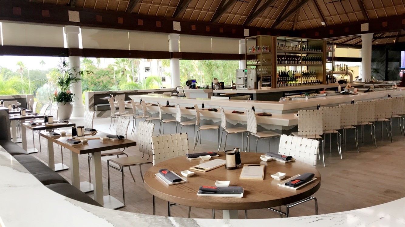 Tables surround the bar at Orchid Lounge, with a view out to the tropical landscaping at Royal Pacific Resort