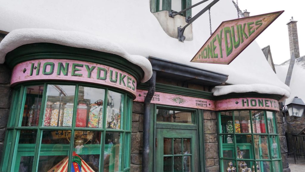 The entrance to Honeydukes in Hogsmeade with window displays full of candies and treats