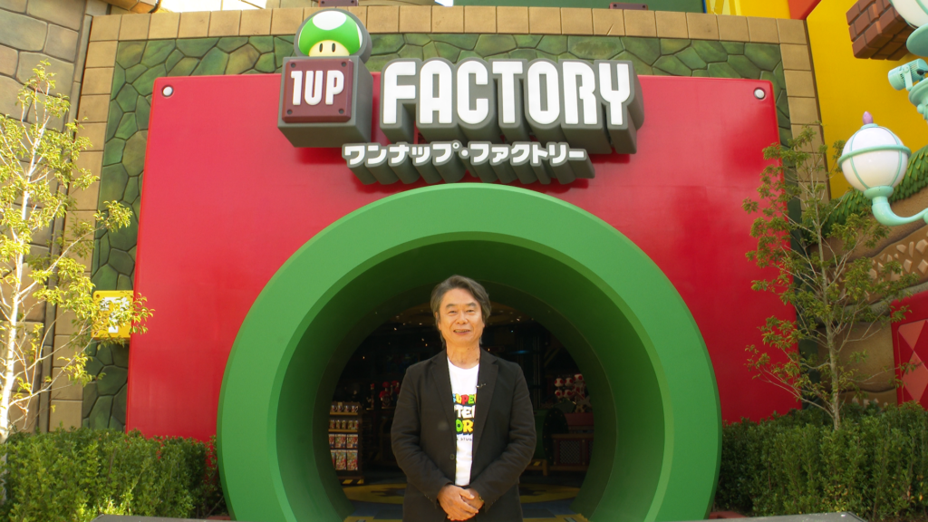 Shigeru Miyamoto at the entrance to the 1-Up Factory at Super Nintendo World