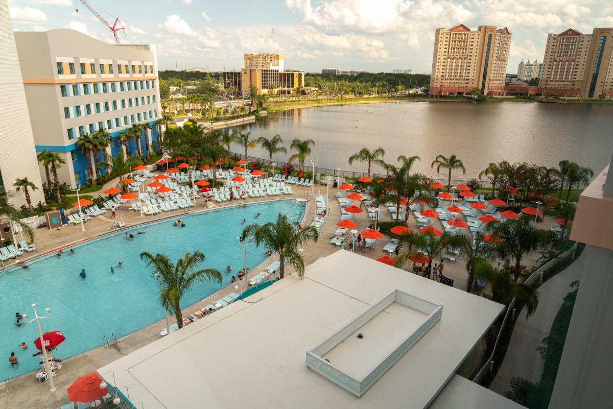 The surfboard-shaped pool at Surfside Inn and Suites is surrounded by beach lounge chairs and palm trees, and lies next to a lake.